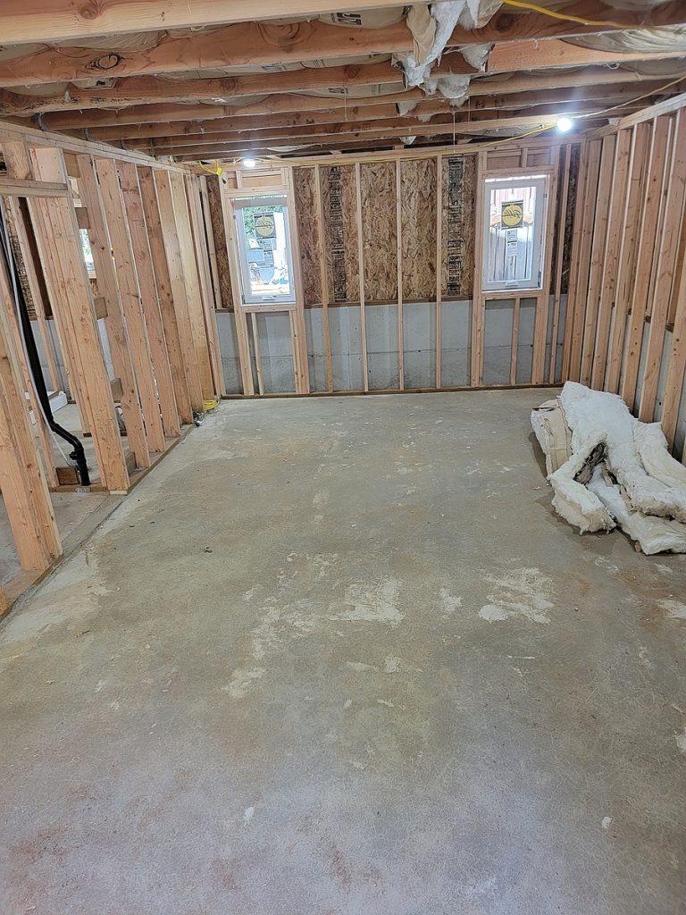 Basement framed out with bare concrete slab, before the apartment build-out