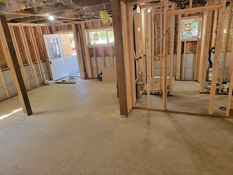 Framed basement with the exterior door open and rough plumbing installed