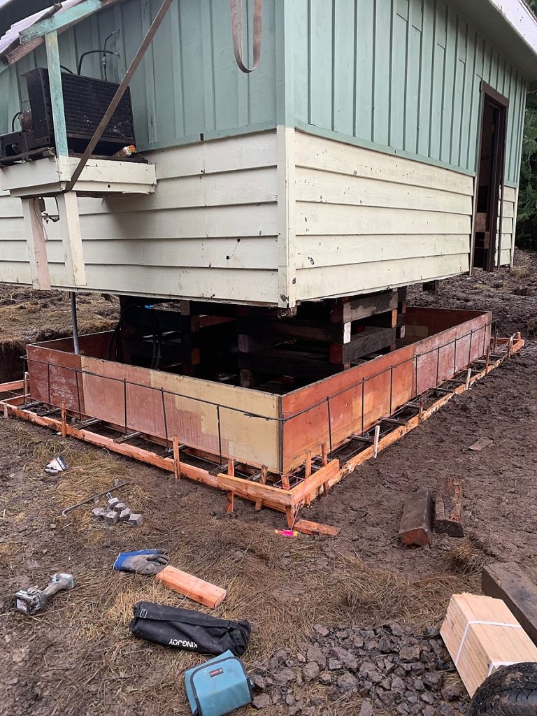 The small building supported on cribbing within new foundation forms
