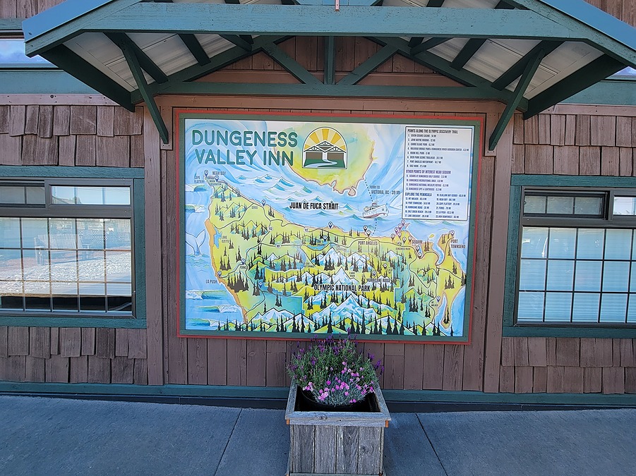 Inn entry beneath a timber gable, with a hand-painted illustrated map of the Dungeness Valley