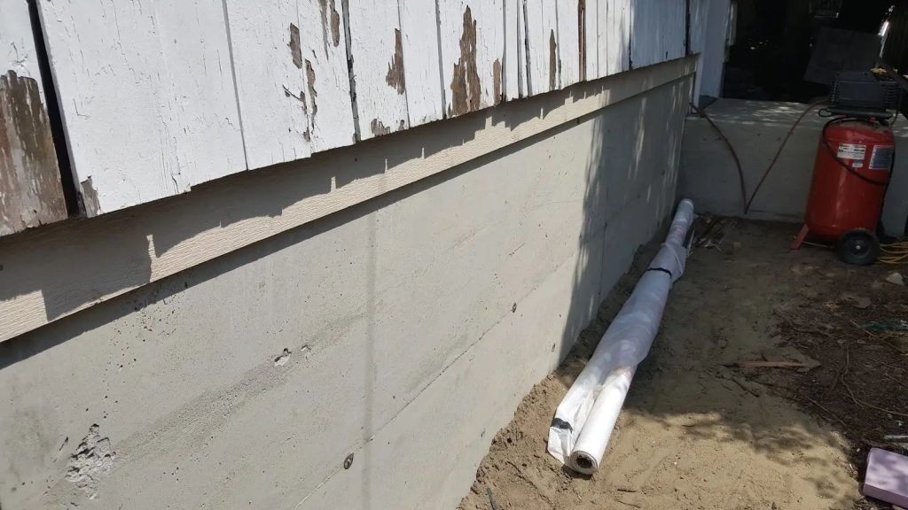 New concrete foundation poured beneath a 1920s Port Angeles garage, with the original structure resting on it