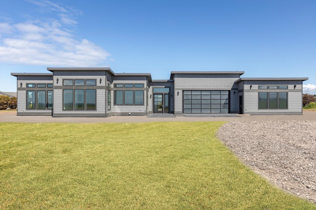 Front elevation of a modern custom home built near Sequim, Washington, with low rooflines and full-height windows