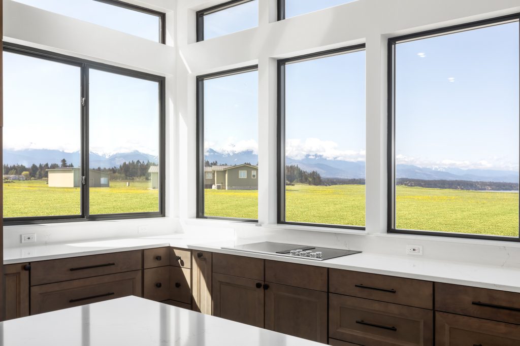 Kitchen counter beneath corner windows looking out to the Olympic Mountains and open pasture