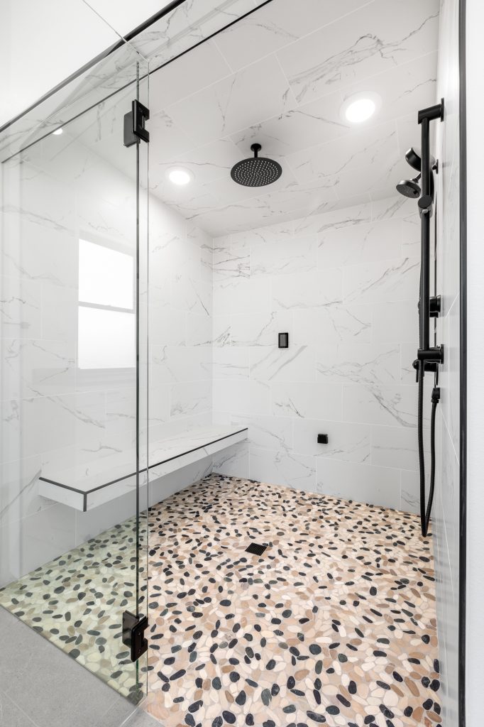Curbless steam shower with large-format marble-look tile, terrazzo floor and matte black fixtures